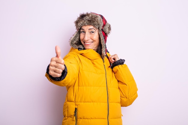 Foto Ältere hübsche frau, die stolz ist und positiv mit daumen nach oben lächelt. winterkonzept