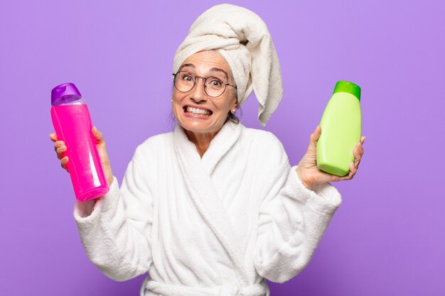 Foto Ältere hübsche frau nach der dusche, die bademantel trägt. konzept für gesichtsreinigungs- oder duschprodukte