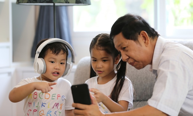 ältere Menschen oder Großvater und Kinder hören Musik und spielen zusammen im Wohnzimmer