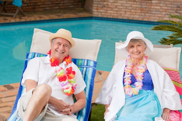 Ältere paare, die sich neben dem swimmingpool hinlegen