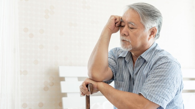 Ältere patienten im bett asiatische seniorenpatienten kopfschmerzen hände auf der stirn medizin- und gesundheitskonzept