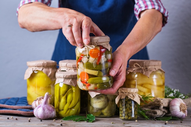 Ältere reife frau, die in den händen glas mit hausgemachtem konserviertem und fermentiertem essen hält. auswahl an eingelegtem und mariniertem gemüse. hauswirtschaft, hauswirtschaft, ernteerhaltung