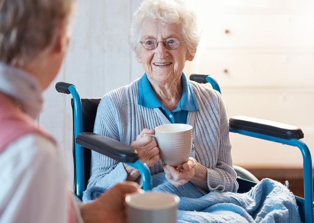 Foto Ältere rollstuhl- und frauenpatientin mit morgenkaffee in einem beratenden medizinischen gespräch