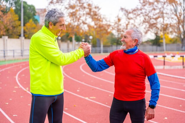 Foto Ältere sportliche freunde schütteln sich stolz die hände nach dem laufen