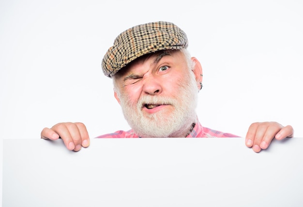 Foto Älterer bärtiger emotionaler mann späht aus bannerplatz ankündigung ältere person ankündigungskonzept veranstaltungsankündigung rentner-großvater im vintage-hat-plakat-informationskopierraum