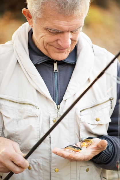 Foto Älterer fischer, der viele fischköder hält.