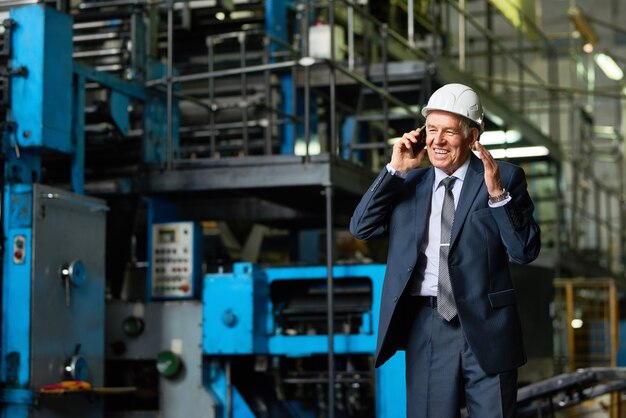 Älterer Geschäftsmann, der in der Fabrik telefonisch spricht