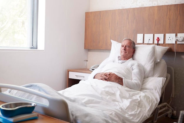 Foto Älterer männlicher patient im krankenhausbett in der geriatrischen abteilung