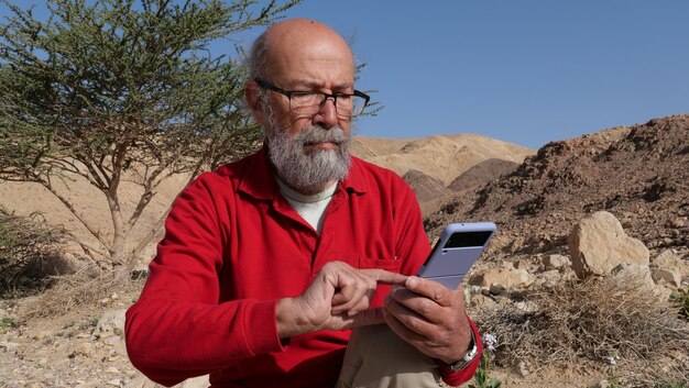 Foto Älterer mann benutzt ein handy in der wüste