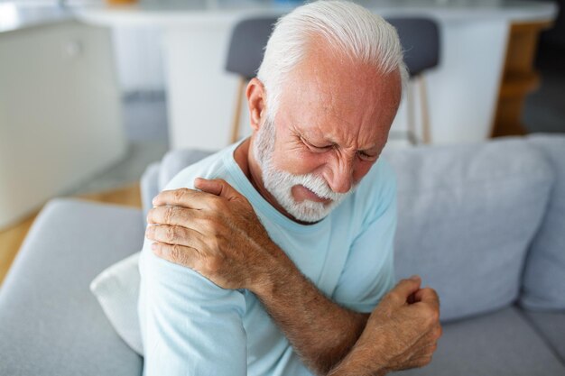 Foto Älterer mann berührt seine schulter, leidet an schulterschmerzen, ischias, sitzender lebensstil, gesundheitsprobleme mit der schulter, krankenversicherung.