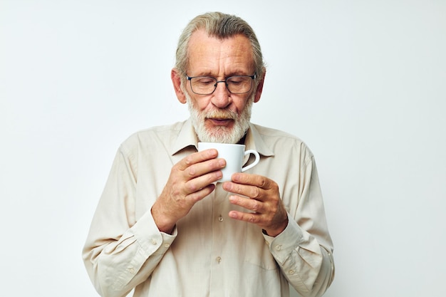 Älterer Mann, der einen Becher auf einem weißen Hintergrund hält