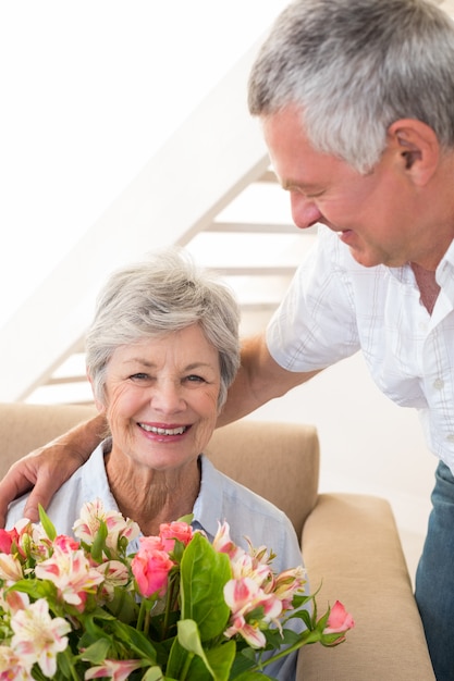 Foto Älterer mann, der seinem partner einen blumenstrauß der blumen lächelt an der kamera gibt