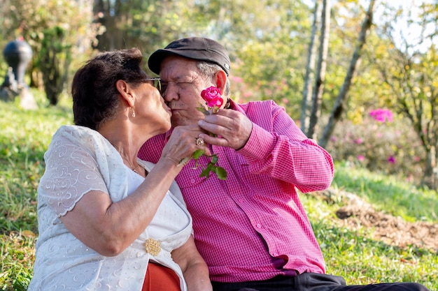 Älterer Mann, der seiner Frau eine Blume gibt und sie im Hof seines Bauernhofs küsst