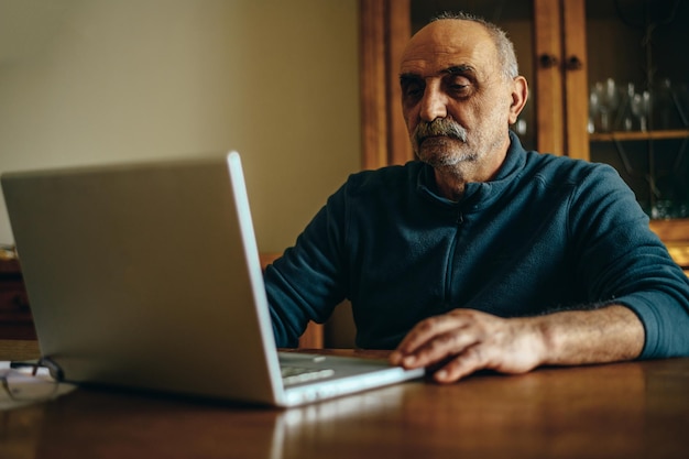 Foto Älterer mann, der zu hause einen laptop verwendet