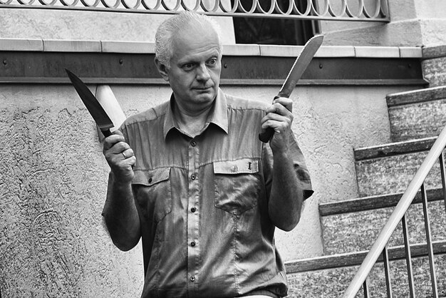 Foto Älterer mann hält messer, während er auf treppen steht