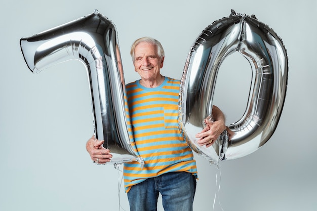 Foto Älterer mann mit silbernen ballons für seine 70. geburtstagsfeier