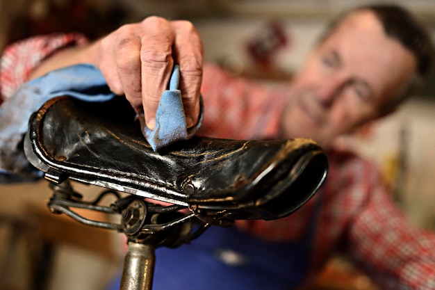 Älterer Mann reinigt Fahrradsitz in seiner Werkstatt, Nahaufnahme