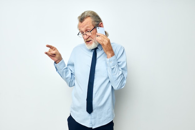Foto Älterer mann spricht am telefon vor weißem hintergrund