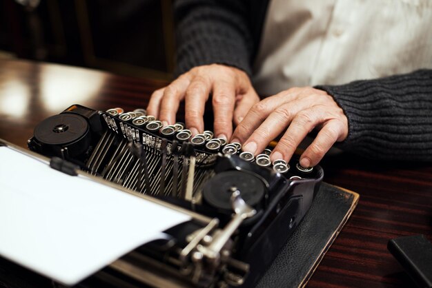 Foto Älterer mann übergibt das tippen auf veralteter schreibmaschine.