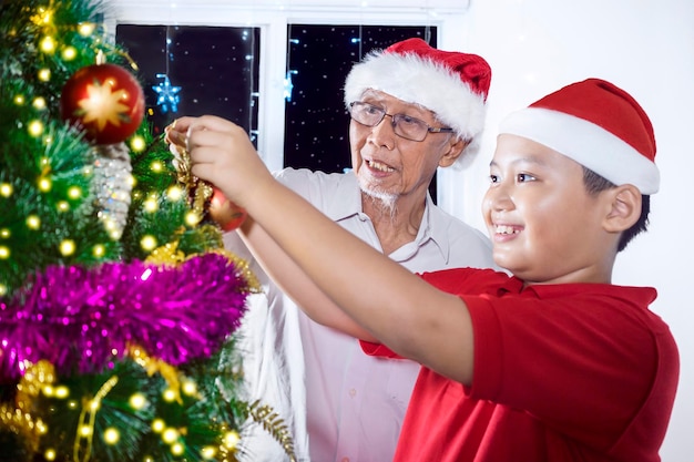 Älterer Mann und Enkelin mit Weihnachtsbaum