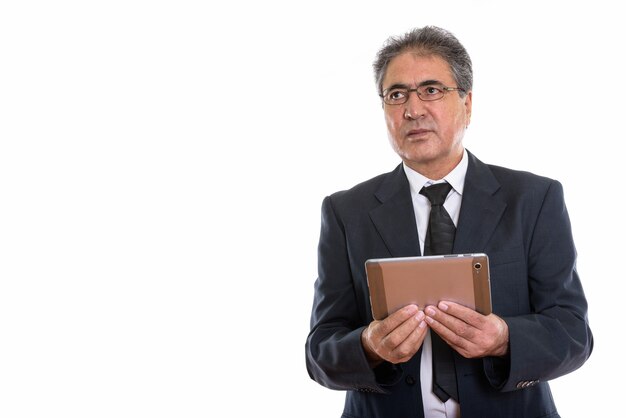 älterer persischer Geschäftsmann, der digitales Tablett hält und Copyspace betrachtet