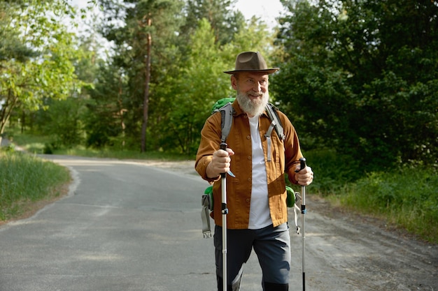 Foto Älterer reifer mann trainiert nordic walking im park und genießt aktive erholung im freien