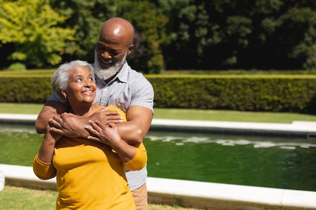 Foto Älteres afroamerikanisches paar verbringt gemeinsam zeit im sonnigen garten, umarmt und lächelt. rückzug, ruhestand und glückliches senioren-lifestyle-konzept.