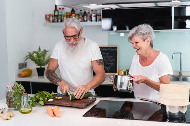 Älteres Paar, das zu Hause kocht, während vegetarisches Mittagessen vorbereitet