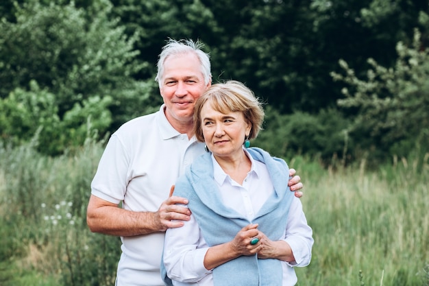 älteres Paar geht in der Natur spazieren und umarmt