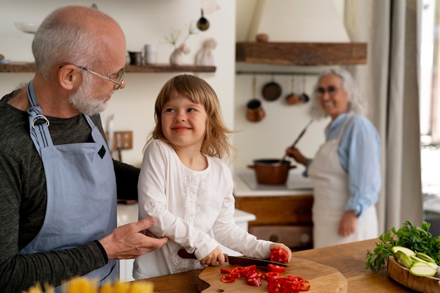 Foto Älteres paar kocht gemeinsam mit enkelkind in der küche