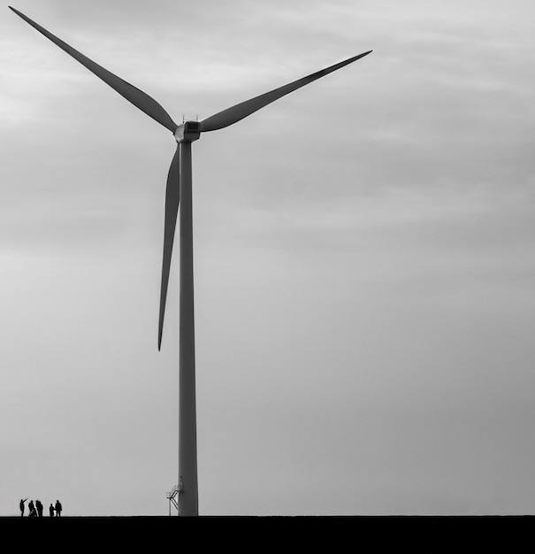 Aerogenerador para la producción de energía eléctrica concepto de minimalismo en blanco y negro con personas para mostrar la escala