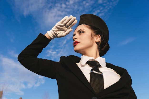 Aeromoça de uniforme contra o céu azul