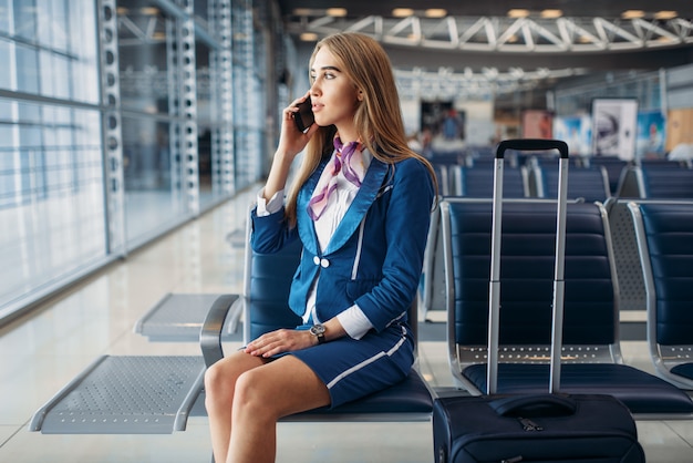 Aeromoça falando ao telefone celular no aeroporto