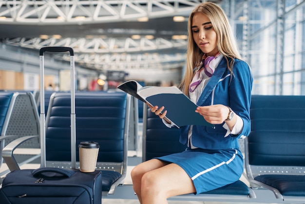 Aeromoça lê revista na sala de espera do aeroporto