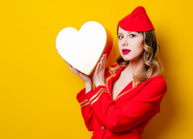 Foto aeromoça vestindo em uniforme vermelho com caixa de gfit feriado de forma de coração