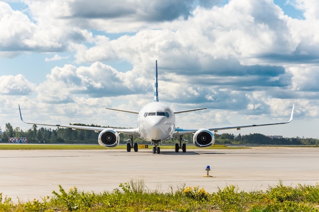 Aeronave na pista de direção do aeroporto, exatamente no meio do quadro, tendo como pano de fundo um céu pitoresco nas nuvens.