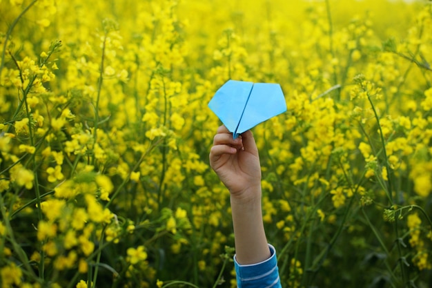 Aeroplano de papel en manos de los niños en fondo amarillo.