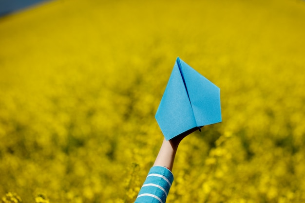 Aeroplano de papel en manos de los niños en fondo amarillo.