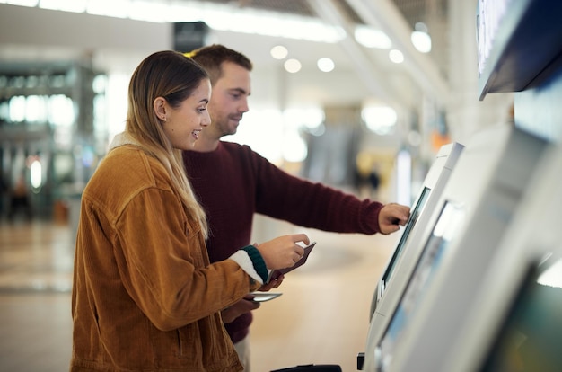 Aeroporto de viagem e casal na máquina de check-in com passaporte e passagem para voo Imigração do dia dos namorados ou homem e mulher felizes no saguão da companhia aérea ou quiosque para cartão de embarque para férias