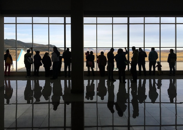 Aeropuerto ocupado con personas de pie cerca del vidrio