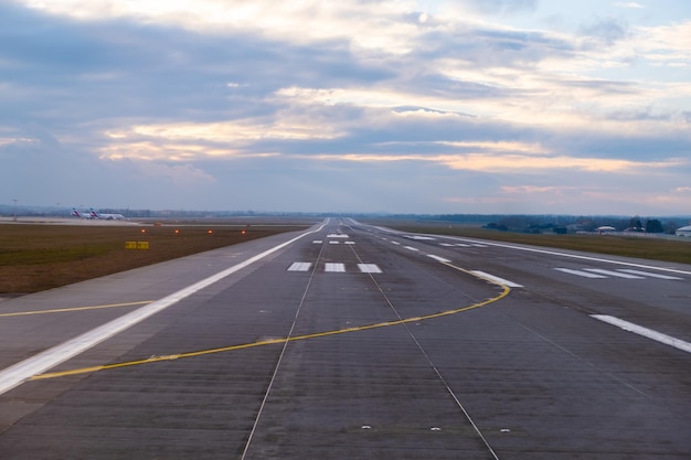 En el aeropuerto, una pista interminable se extiende hasta el horizonte con prominentes marcas de aviones y wel