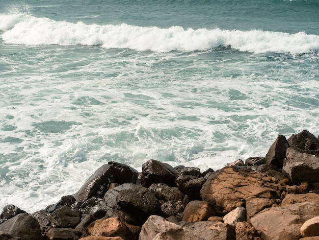 Aerosol blanco de las olas del mar golpeando las piedras