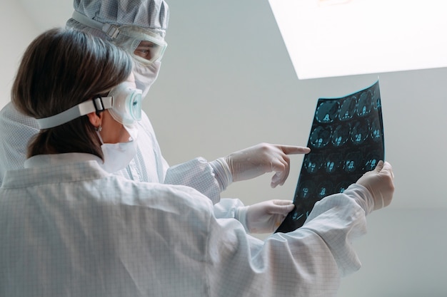 Foto Ärzte, die auf weißem hintergrund stehen, untersuchen röntgenaufnahmen auf lungenentzündung eines covid-19-patienten in der klinik. coronavirus-konzept.