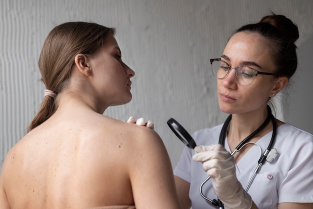 Foto Ärztin diagnostiziert ein melanom am körper einer patientin