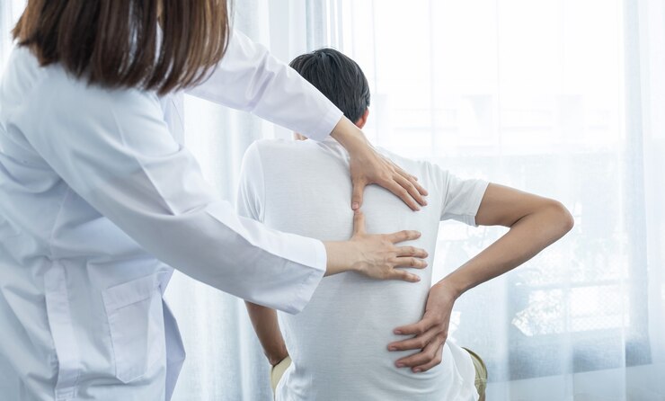 Ärztin Hände tun Physiotherapie Durch die Verlängerung des Rückens eines männlichen Patienten.