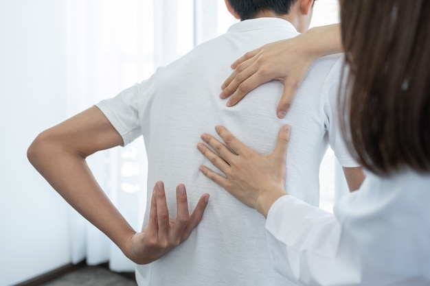 Ärztin hände tun physiotherapie durch die verlängerung des rückens eines männlichen patienten.