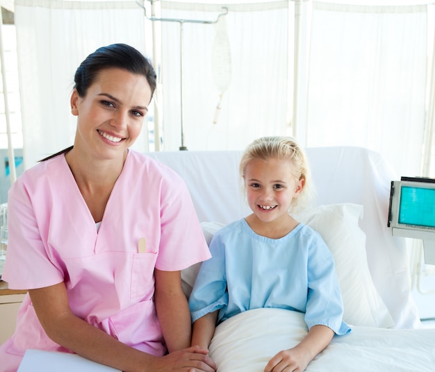 Foto Ärztin mit ihrem kleinen patienten, der auf einem krankenhausbett sitzt