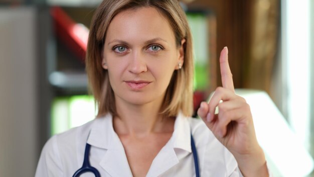Foto Ärztin zeigt mit dem finger nach oben im arztpraxiskonzept der warnaufmerksamkeit und medizin