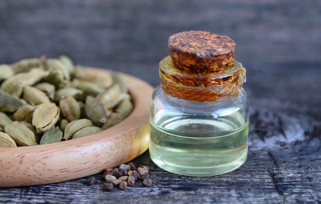 Foto Ätherisches kardamomöl in einer glasflasche auf altem holztisch. elettaria cardamomum-extrakt.