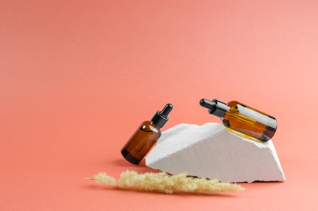 Ätherisches Öl oder Serum in einer braunen Flasche mit Tropfer Kosmetik-Körperpflege Aromatisierte Ölflasche auf weißem geometrischem Podium